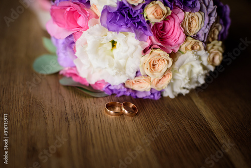 Close up of engagement rings  rose flower bouquet on the wooden table. 