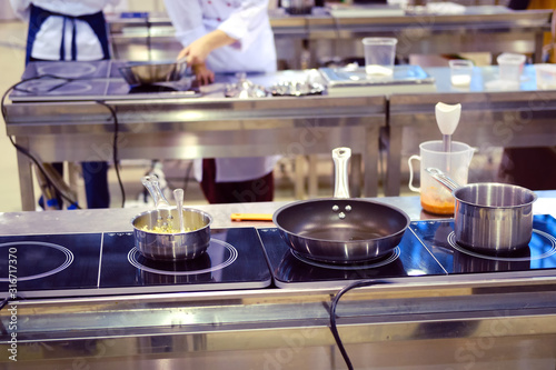 Pans and dishes on an electric stove in the kitchen of a restaurant or cafe