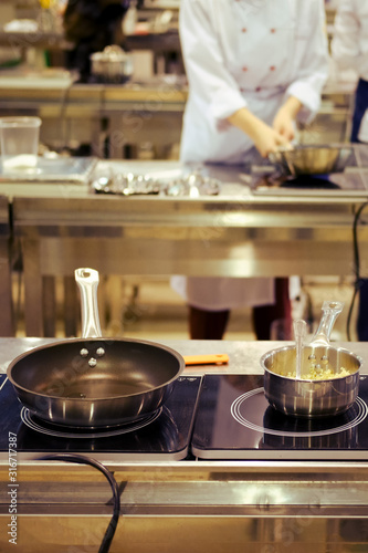 Pans and dishes with food on an electric stove in the kitchen of a restaurant or cafe