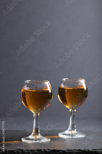 Glass of whiskey on a black stone slate board on black background. Side view, copy space.