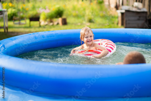 little girl swims in an inflatable pool in a life buoy and laughs