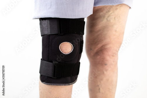 Old person legs with one knee in a protective knee brace