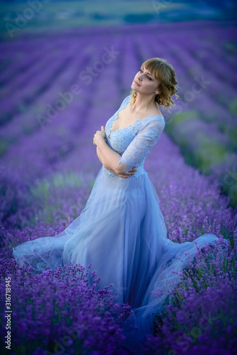 A woman in a bride's dress on her wedding day walks through a field of lavender flowers.