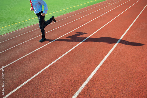 Unrecognizable businessman running along empty track with his shadow © PeskyMonkey