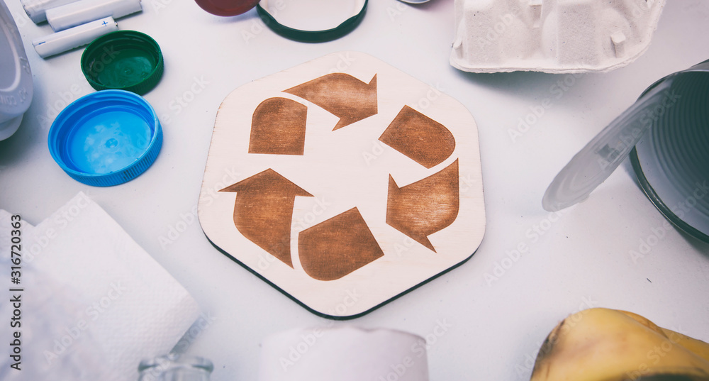 A lot of different garbage on the table and the recycling icon between them A lot of different garbage on the table and the recycling icon between them