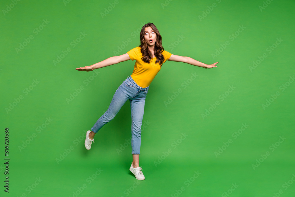 Full length photo of pretty funny lady holding arms by sides going to fly open mouth big eyes wear casual yellow t-shirt jeans isolated bright green color background