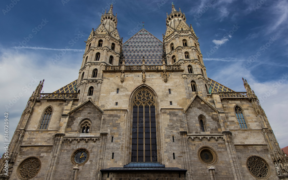 Cathedral religion medieval architecture building symmetry exterior facade front side two towers foreshortening from below on vivid blue sky background space, Vienna capital of Austria touristic site