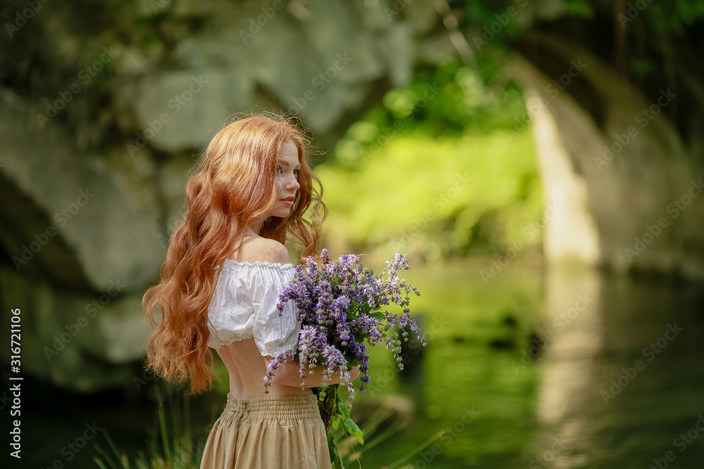 Naklejka premium A woman in a long dress walks near the forest old bridge over the river.