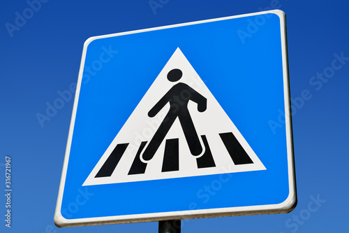 Pedestrian Crossing sign against a blue sky