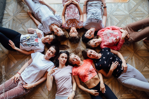 Top view of nine happy beautiful women laying on the floor.