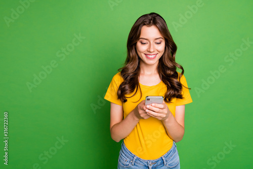 Portrait of her she nice attractive lovely pretty charming cute cheerful cheery wavy-haired girl writing sms message chatting online isolated on bright vivid shine vibrant green color background