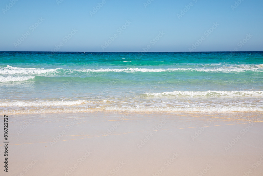 Cloudless sky over a colorful sea with diferent colors aquamarine turquoise dakr blue azure with waves prducing white foam crushing against a yellow beach summer sumertime sunny calm water tranquil Cloudless sky over a colorful sea with diferent colors aquamarine turquoise dakr blue azure with waves prducing white foam crushing against a yellow beach summer sumertime sunny calm water tranquil