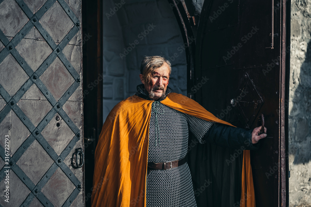 Naklejka premium Portrait of a medieval senior warrior man in armor after a battle with dirty and blood-smeared face