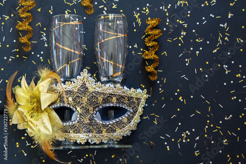 golden venetian mask with champagne glasses and confetti on black background photo