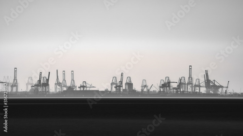 Obraz na plátne Commercial port silhouette in the horizon with cranes, long exposure