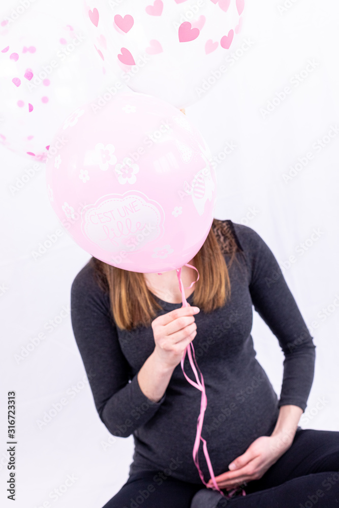 Fototapeta premium Young pregnant woman sitting with balloons - Gender Reveal - It's a Girl !