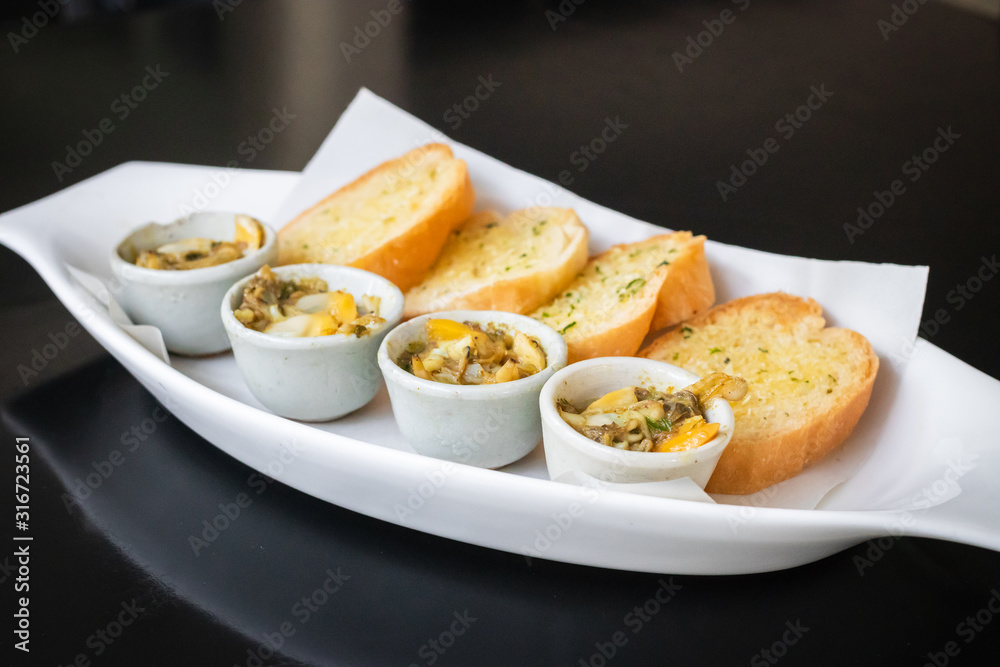 Baked baby clams with butter, onions, parsley served with garlic and butter french bread.