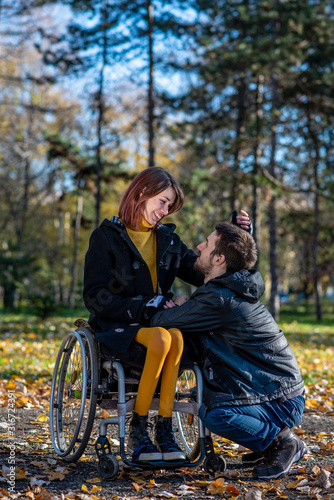 Young disabled woman in a wheelchair with boyfriend. Man with disabled girl in a wheelchair