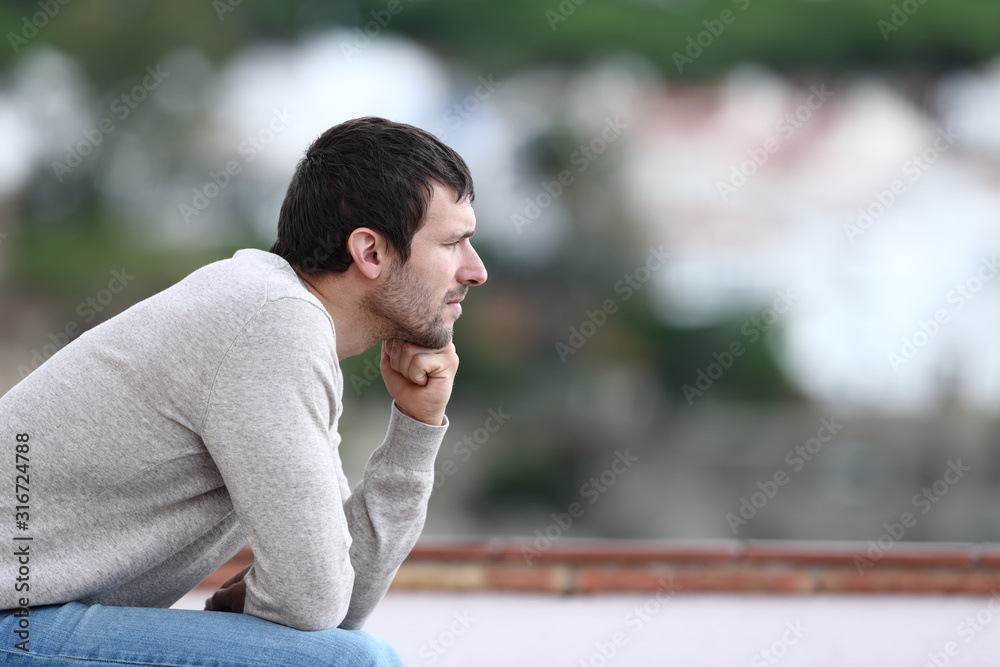 Worried man thinking looking away sitting on a bench - obrazy, fototapety, plakaty 