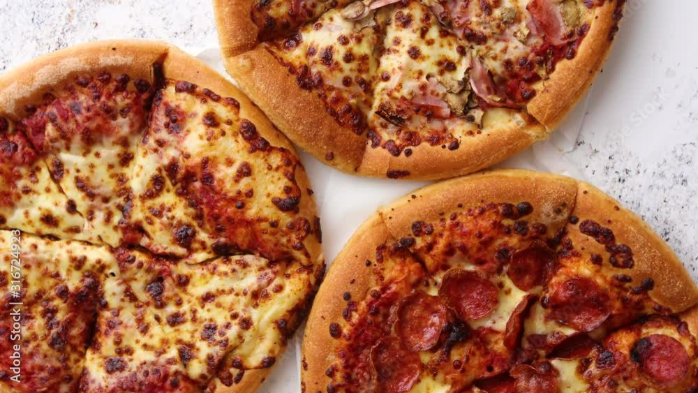 Three american style pizzas served on a table Three american style pizzas served on a table