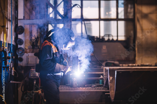 Worker welding in oxygen mask in a factory photo