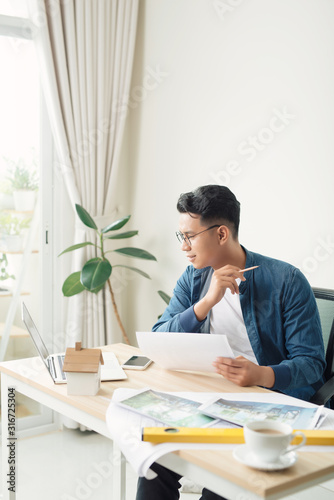 Profile shot of a young male architect working on blueprints at his desk at the office copyspace building plans construction project engineer expert specialist qualified job occupation © makistock
