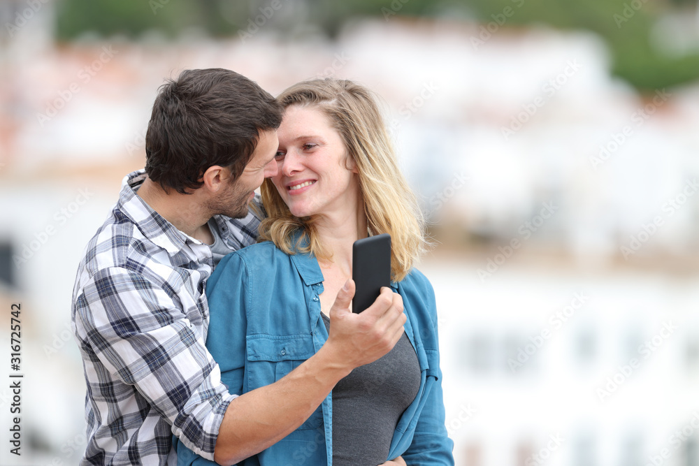 Happy couple flirting holding smart phone