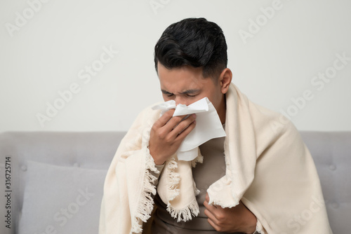 Obraz na płótnie Sick man  blowing nose and sneeze into tissue