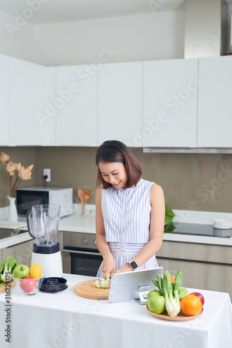 Healthy Asian woman enjoy making green vegetables detox cleanse and green fruit smoothie with blender in kitchen at home. dieting concept.healthy lifestyle