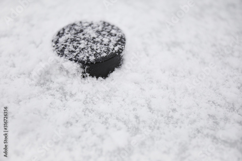 Sports background close up of hockey pluck on snowy ice outdoors, copy space