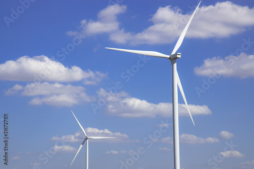 Wind turbine in blue sky with clouds background. Clean energy, renewable energy and ecology concept.