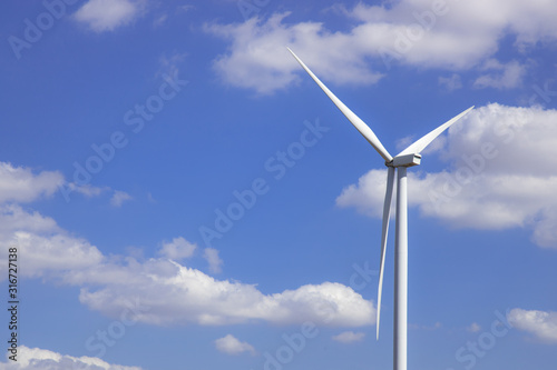 Wind turbine in blue sky with clouds background. Clean energy, renewable energy and ecology concept.