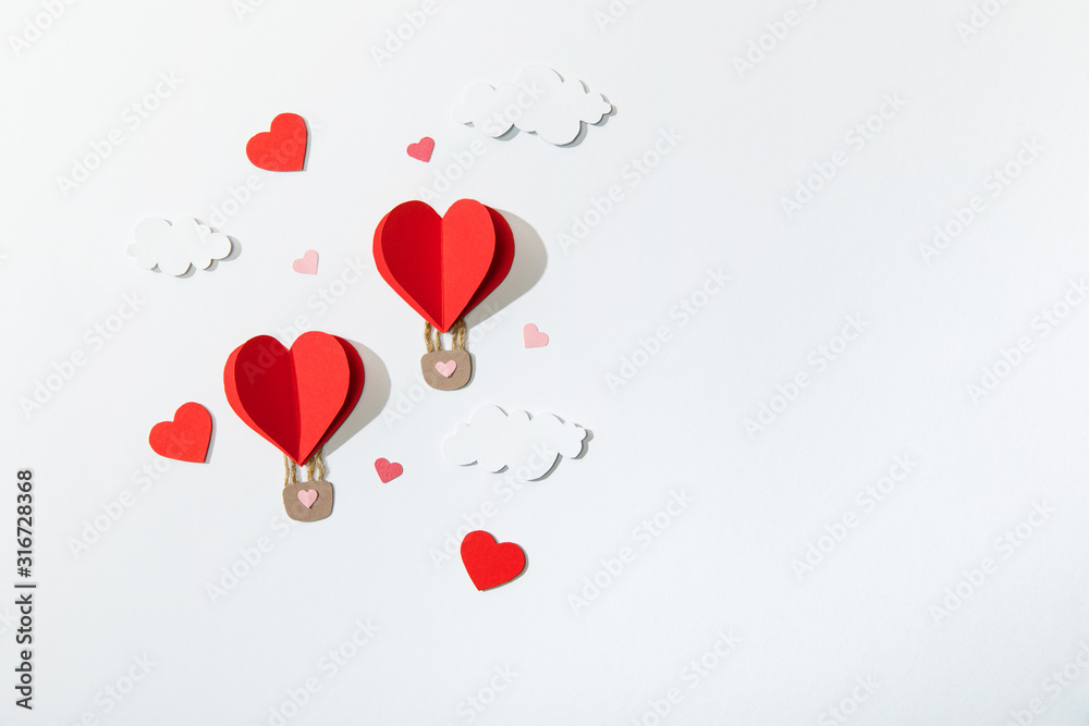 top view of paper heart shaped air balloons in clouds on white background
