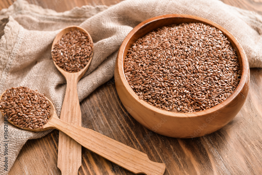 Bowl with flax seeds and spoons on wooden background Bowl with flax seeds and spoons on wooden background