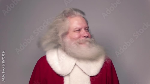 Senior Caucasian smiling man in Santa Claus suit with splendid grey hair, mustache and beard, turning his head from side to side. Funny portrait of handsome European people white background close up.