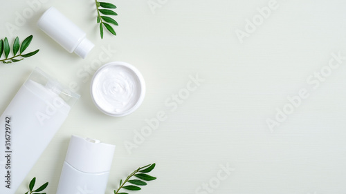 Organic SPA cosmetic products and green leaves. Top view body cream, shampoo bottle, essential oil for hair, shower gel. Natural cosmetic, SPA treatment concept. Banner mockup for beauty salon