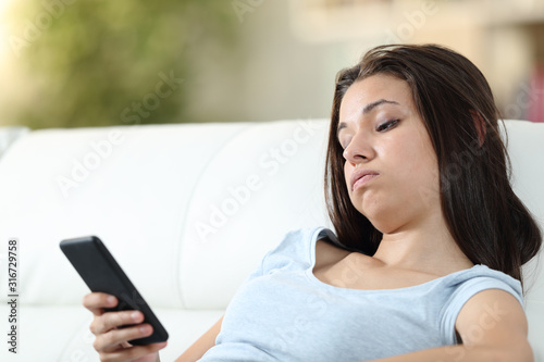 Bored girl checking mobile phone at home photo