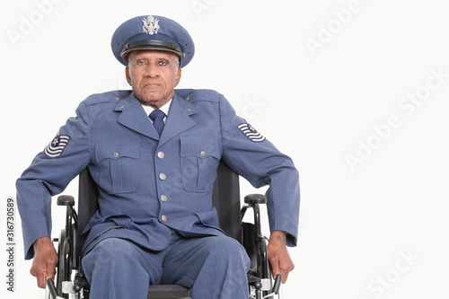 Portrait of a disabled senior male US Air Force officer in wheelchair over gray background photo