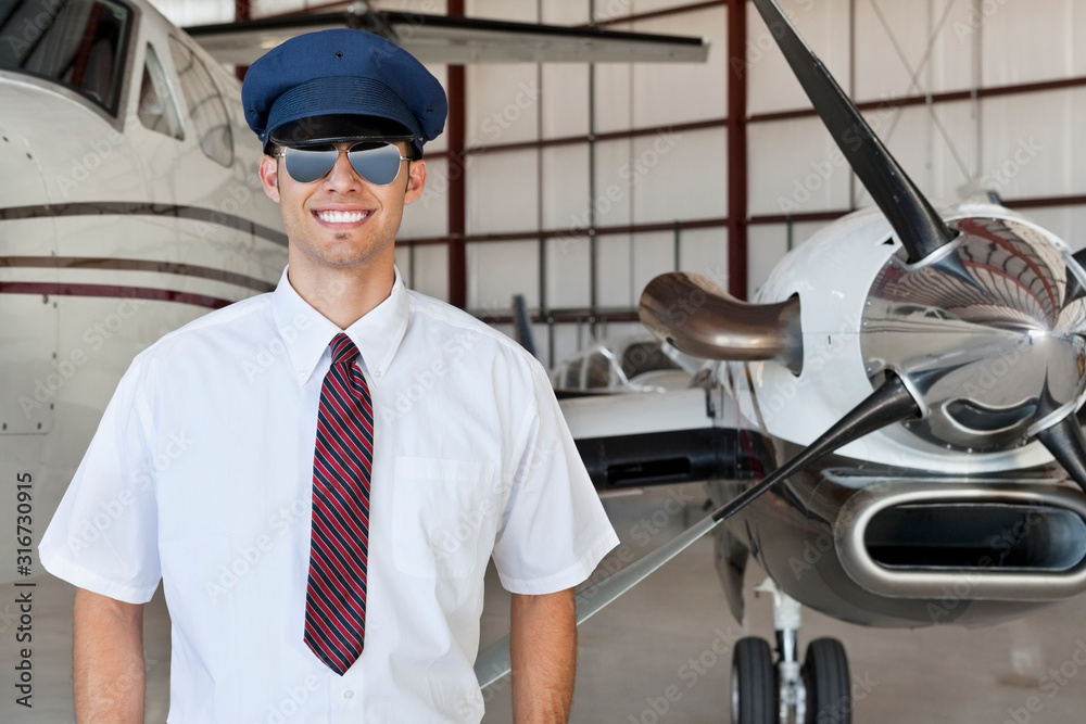 Portrait of handsome young pilot standing in front of airplane Portrait of handsome young pilot standing in front of airplane