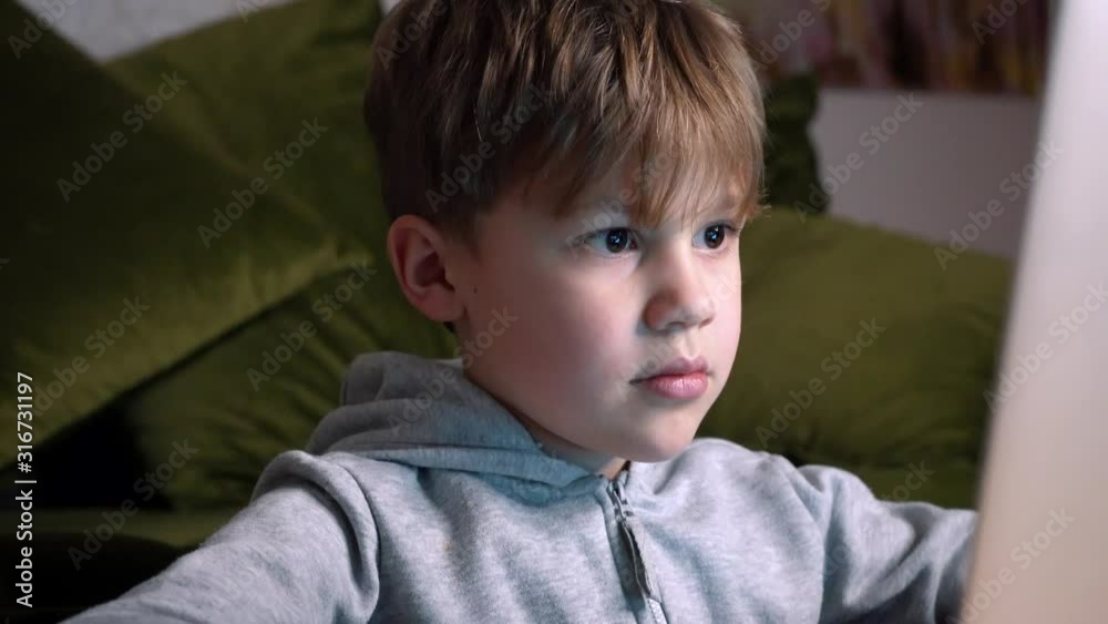 Child playing video games and using computer. Boy is Focused Looking At Computer Screen. Futuristic rgb backlights Child playing video games and using computer. Boy is Focused Looking At Computer Screen. Futuristic rgb backlights