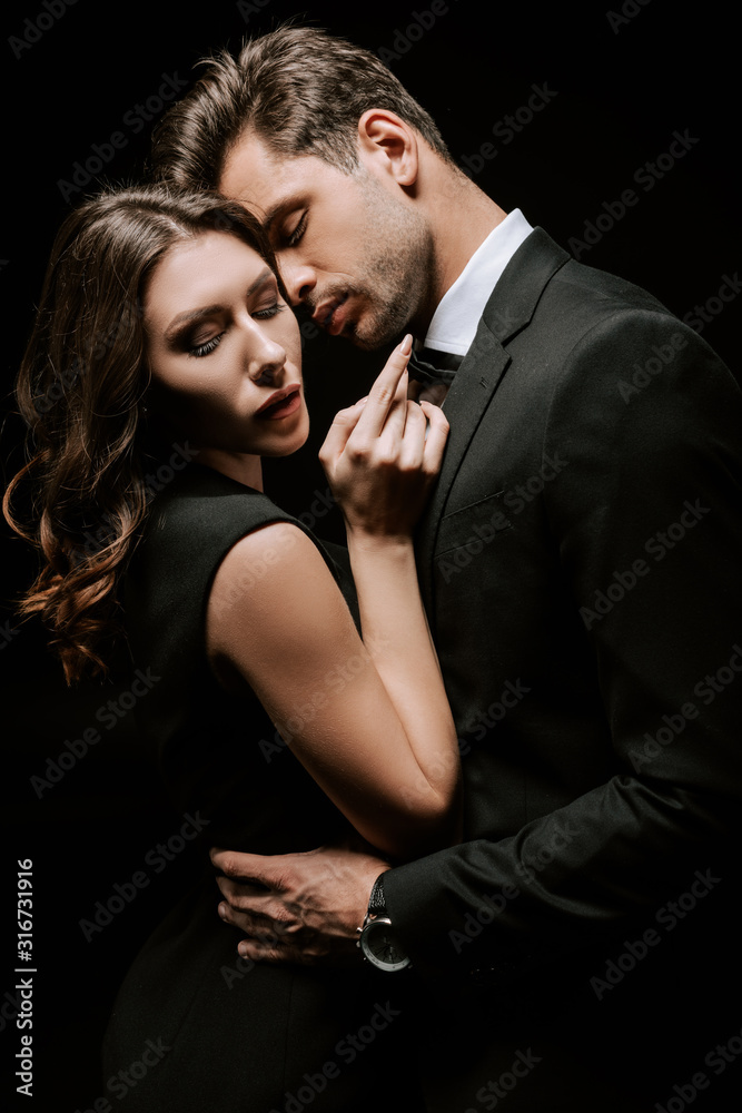 handsome man hugging young attractive woman isolated on black