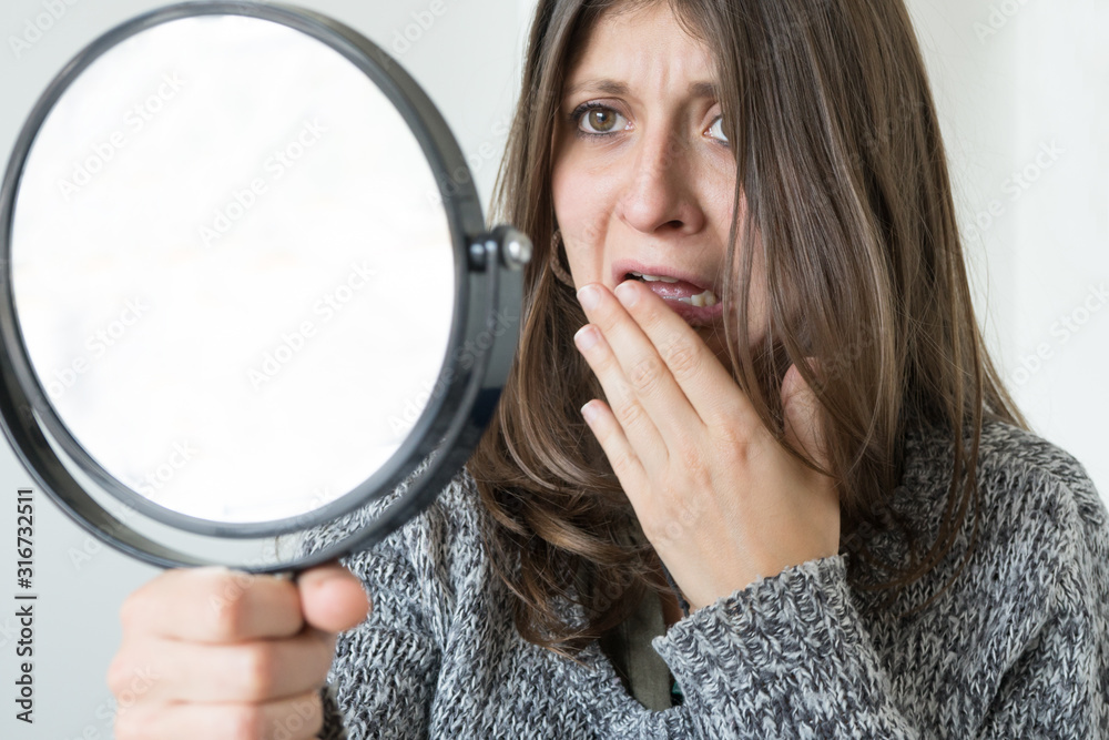 Dissatisfied cute girl looks in the mirror with scared look. Dissatisfied cute girl looks in the mirror with scared look.