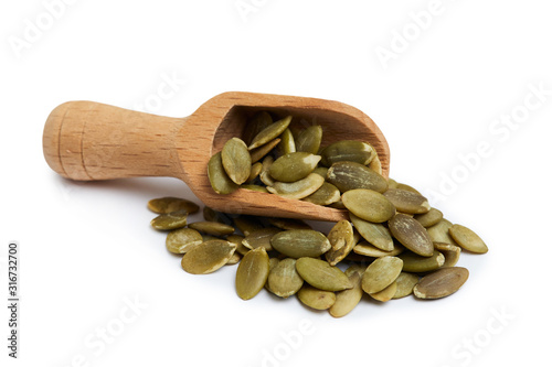 Raw shelled pumpkin seeds in wooden scoop isolated on white background