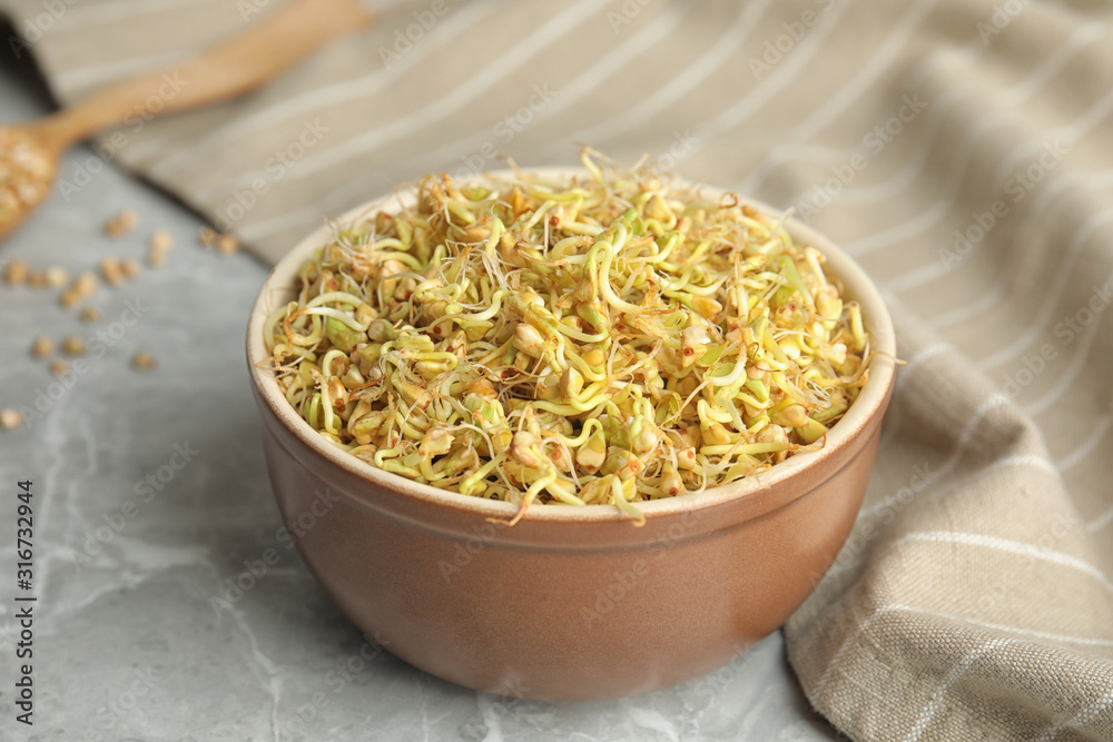 Bowl of sprouted green buckwheat on light grey table