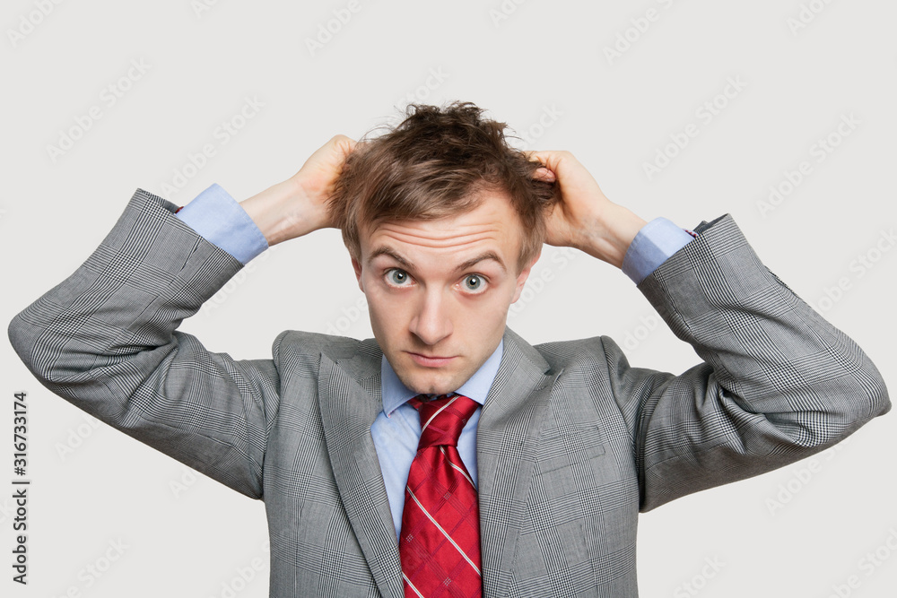 Front view of young businessman in confusion scratching head over colored background Front view of young businessman in confusion scratching head over colored background