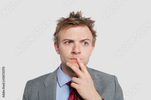 Close-up of young businessman thinking hard over colored background