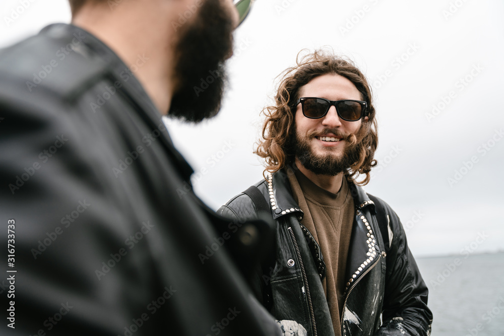 Fototapeta premium Photo of bearded joyful men bikers smiling and talking while standing