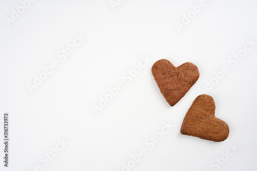 Two heart shape gingerbread cookies on white background. Valentine, love, invitation, recipe, card concept. Top view, flat lay, copy space