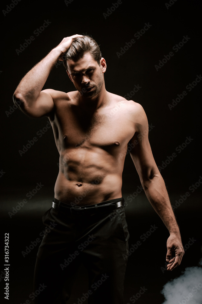 shirtless man touching hair on black with smoke