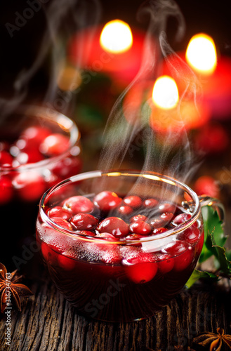 Cranberry mulled wine with aromatic cinnamon  anise and cloves in glass cups on a wooden table  close-up. Christmas hot drink